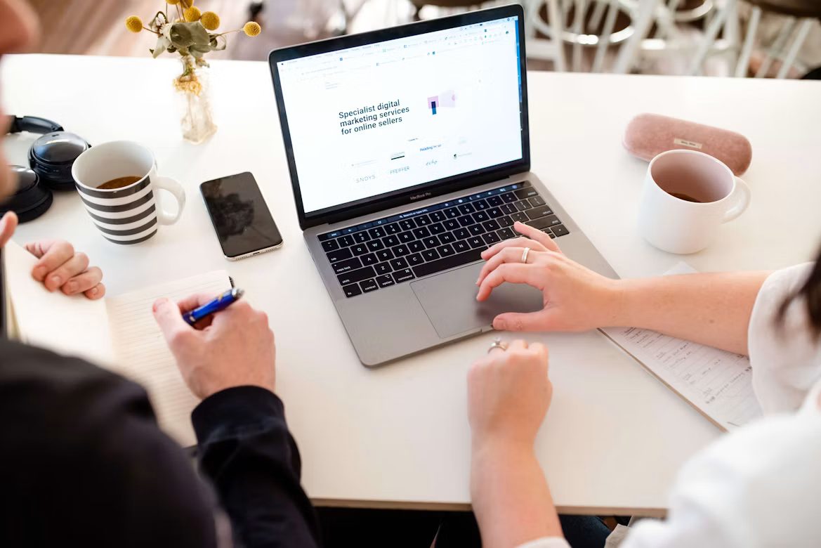 Deux personnes travaillant ensemble sur un ordinateur portable affichant un site web